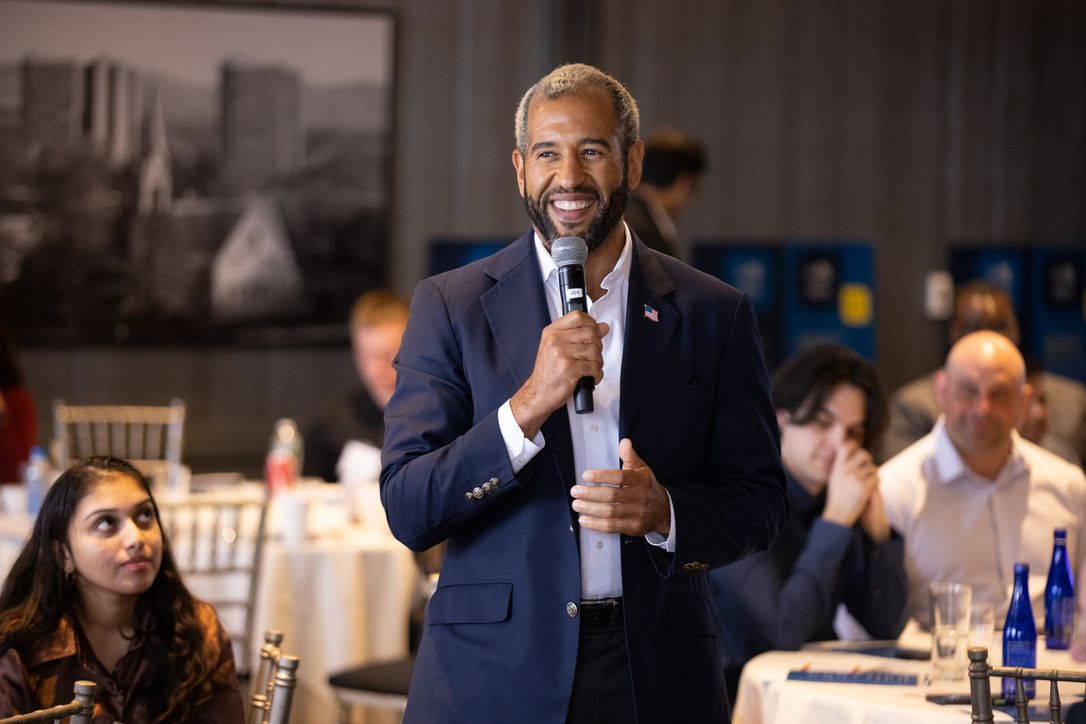 Ian Cain smiling with a microphone at a business event